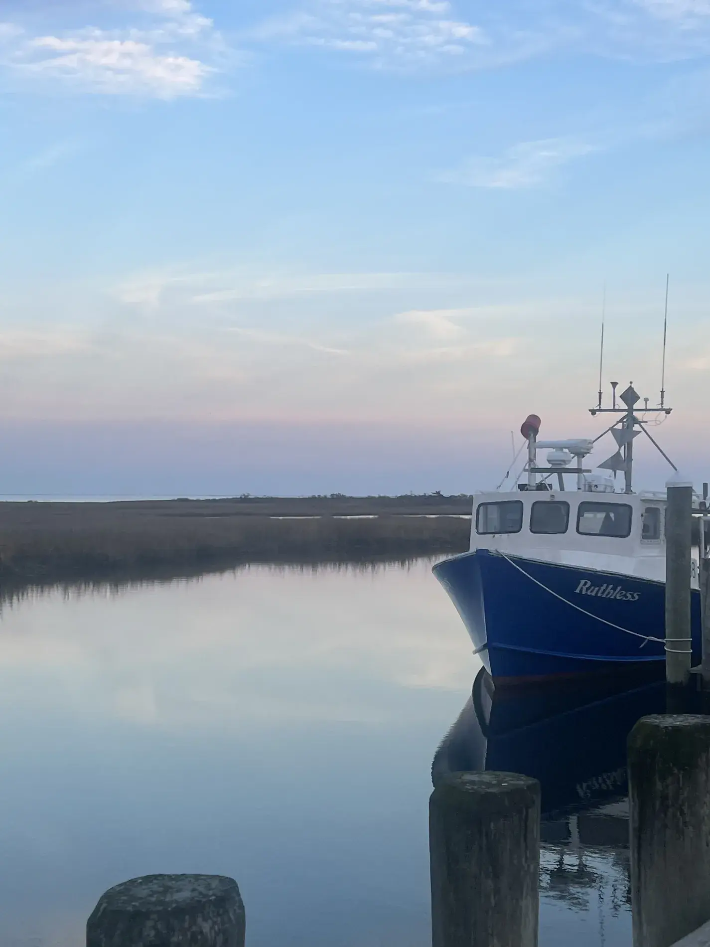 Quiet coastal marina with a working boat at dusk